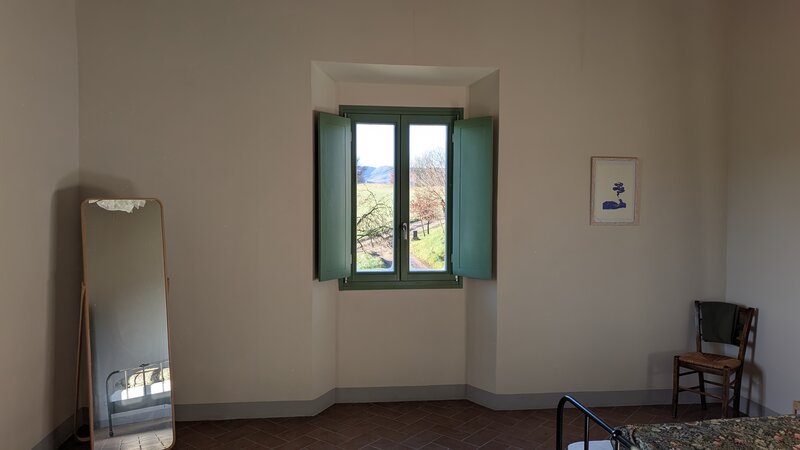 Camera Bianca: finestra centrale con telaio salvia, specchio a muro, sedia antica