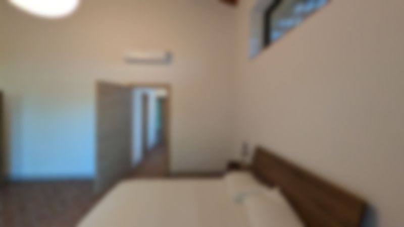 Camera Fattori: letto matrimoniale, porta aperta sul corridoio, travi in legno