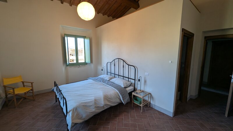 Camera Flaminia: letto matrimoniale, lampadario sferico, sedie regista gialle