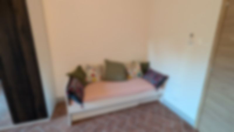 Camera Garzoni: letto-divano bianco con cuscini a fiori, pavimento in cotto